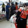 A stylishly dressed Chinese woman looking at a merchant's wares.