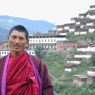 Monk Tashi Phuntsok with the monastery in the background.