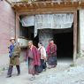 Tibetan laypeople and a nun circumambulating a monastery building.