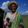 An elderly nomad spinning his prayer wheel and counting his rosary.