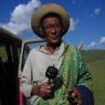 An elderly nomad spinning his prayer wheel and counting his rosary.