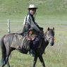 A nomad woman travelling on horseback.