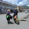 A Tibetan couple riding yaks decorated for the festival on the street in Serta.