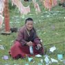 A young monk holding the reins of two horses.