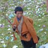 A young boy holding sticks of incense near the cairn.