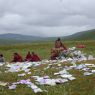 A monk reciting a religious text near the cairn.