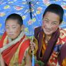 Two young monks under an umbrella on top of the hill.