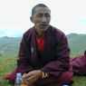 A monk eating on top of the hill.