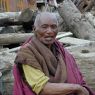 An elderly monk resting on a log.