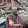 An elderly monk resting on a log.