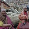 Elderly monks resting on some logs.