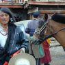 A long haired nomad man leading horses on the street.