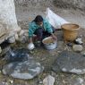 Woman washing barley at village water source