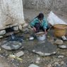 Woman washing barley at village water source