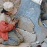 A young girl carving a prayer stone.