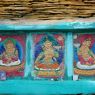 Close-up of painted carvings of buddhas framed in a pile of prayer stones. ??