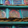 Close-up of painted carvings of buddhas framed in a pile of prayer stones. ??