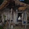 Woman receives guest with a smile from inside the hut