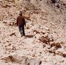 An assistant with measurement tape in hand walking along the terrace created by the retaining wall of the north sector.