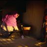 Woman using the quern at House31 Surna standing watching