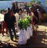 Three 'plah' covered in white cloth 'pae lava' with bunches of leaves at the top waiting to be dressed. Men unwinding the 'gyan'