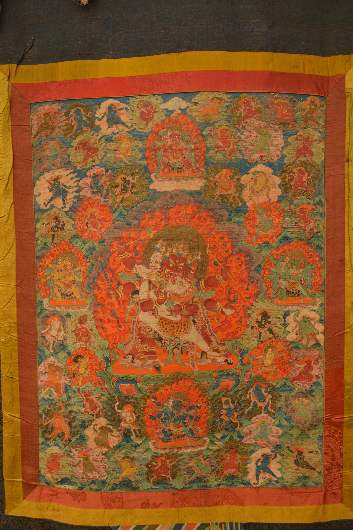 Thangka painting of wrathful deity of three head surrounded by many ...