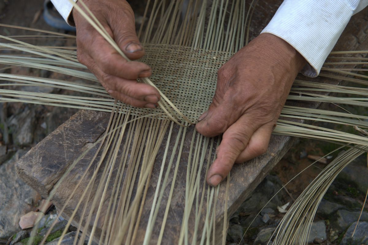 A man weaving Bhutanese bamboo sieve in rural village of Lotokuchu ...